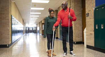 A blind O&M instructor shows a blind teenage girl the best way to use her long white cane.