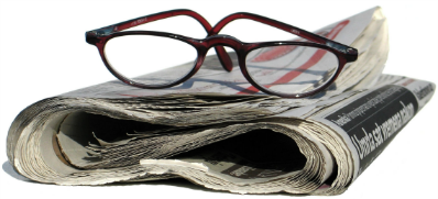 A pair of glasses sits on top of a newspaper