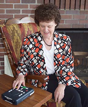 A woman listens to NFB-NEWSLINE using an NLS Player.